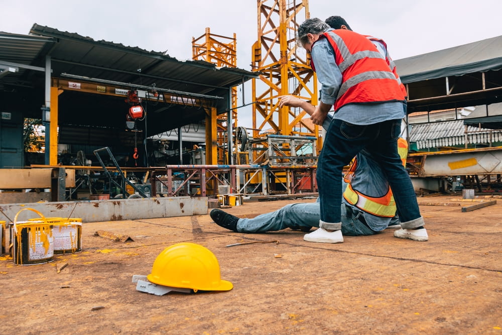 Injured construction worker receiving assistance after workplace accident caused by another employee