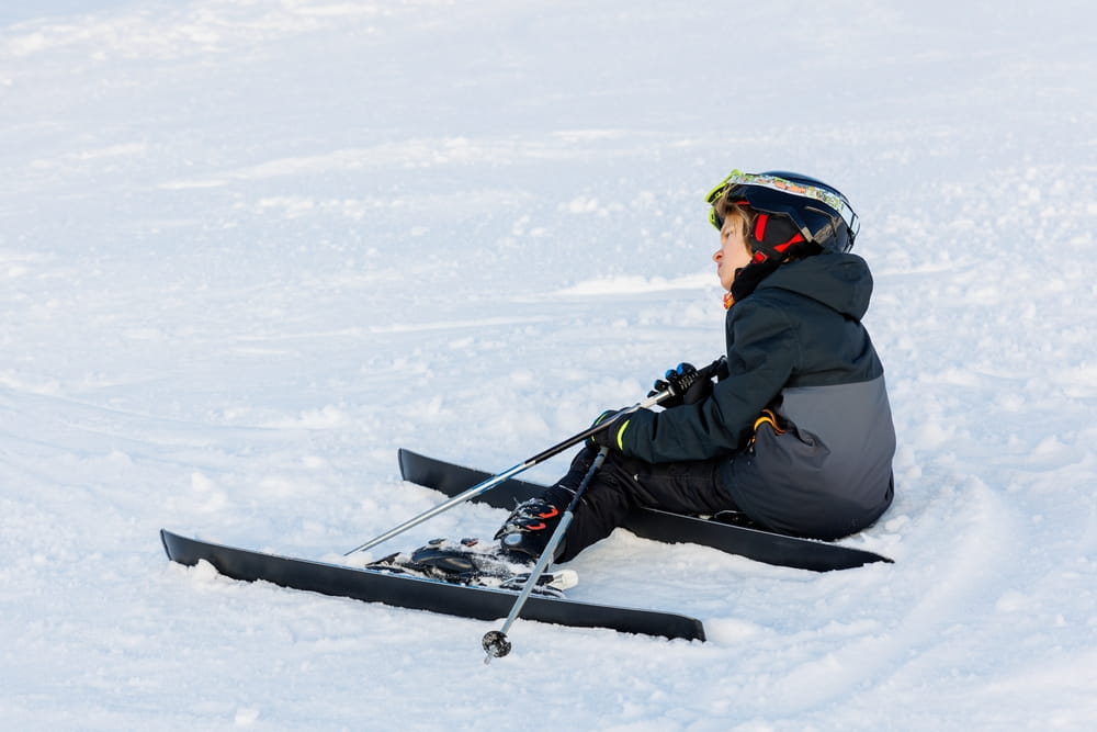 Beginner skier sitting on slope creating potential collision hazard